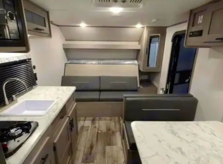 Modern RV rental interior showing kitchen, living space, dinette, and fold-down bed.. Dutchmen Coleman Lantern LT 2021