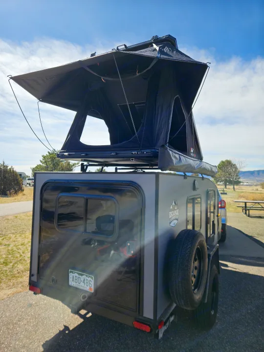 This grey adventure RV rental camper trailer is set up with a rooftop tent, ready for your outdoor escape.. Escapade Ridge 2018
