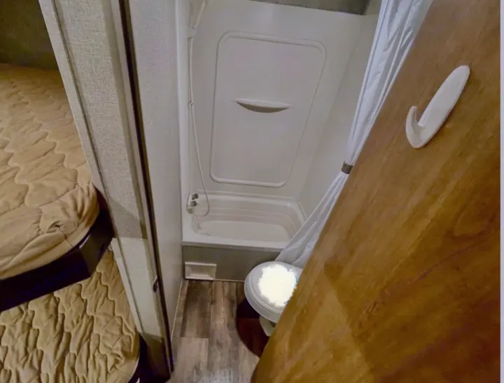 RV rental: compact bathroom with shower and toilet. Cozy bunk beds are visible on the left side of this RV interior.. Keystone RV Summerland 2017