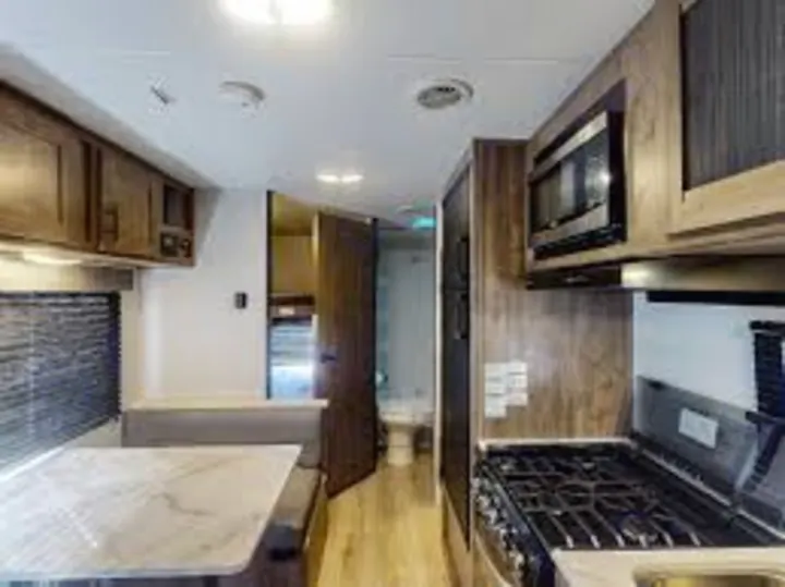 Explore this RV rental's bright interior: modern kitchen, dinette, and hallway leading to the compact bath.. Heartland RVs Pioneer 2017