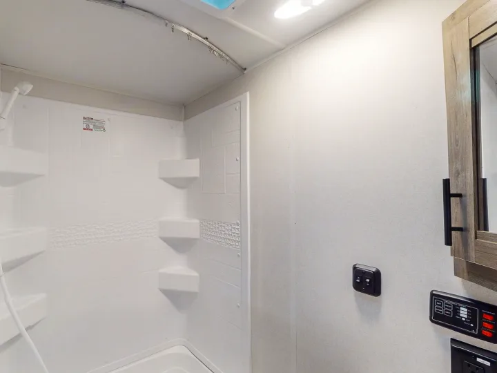 RV rental interior: Bright, white shower stall with built-in shelves & controls. A compact, clean bathroom for your travels.. Heartland RVs Pioneer 2017