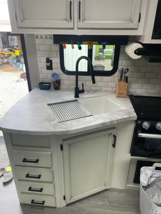 Spacious RV rental kitchen showcasing a modern sink, black faucet, white subway tile, and elegant marble-look counters.. Jayco Jay Flight 2022