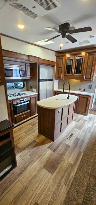 Modern RV rental kitchen with an island, full appliances, and warm wood cabinetry. Ideal for travel adventures.. K-Z Manufacturing Durango 2021