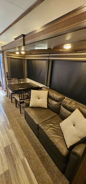 Spacious RV rental interior featuring a comfortable living area with a leather sofa, dining table, and soft lighting.. K-Z Manufacturing Durango 2021