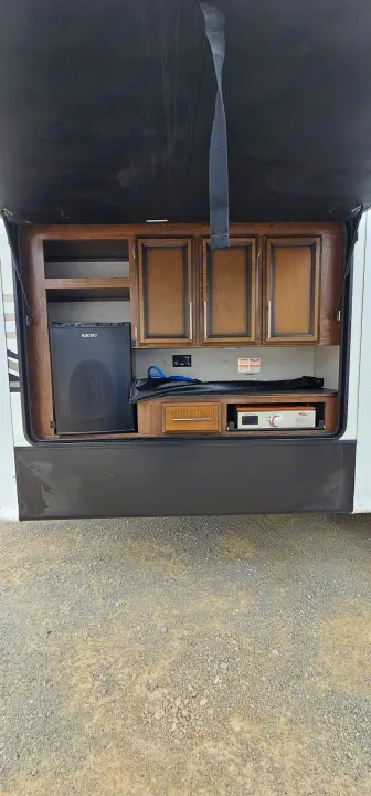 Outdoor kitchen area of an rv rental, featuring an Ascoli mini-fridge, storage, and a Blackstone griddle for camping meals.. K-Z Manufacturing Durango 2021