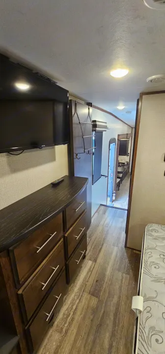 Explore this RV rental's cozy interior, featuring a bedroom with TV/dresser, and a compact hallway leading to the main living area.. K-Z Manufacturing Durango 2021