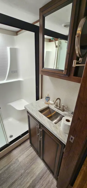 Modern RV rental bathroom featuring a spacious shower with a built-in seat and a sleek vanity sink.. K-Z Manufacturing Durango 2021