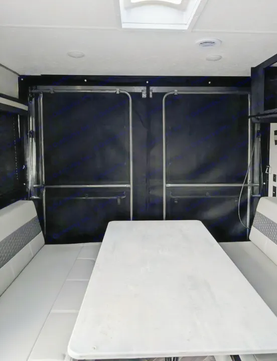 RV rental interior: dining area with a table & bench seating, facing a large, closed toy hauler ramp.. Forest River 2700TH 2021