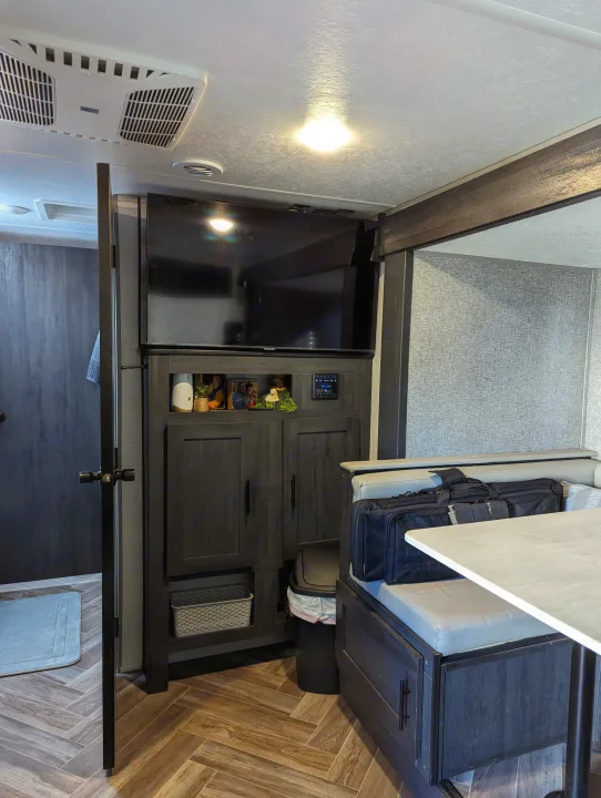 An RV rental interior featuring a cozy dinette, entertainment center, and bathroom access. Ready for your next adventure.. Forest River 2700TH 2021