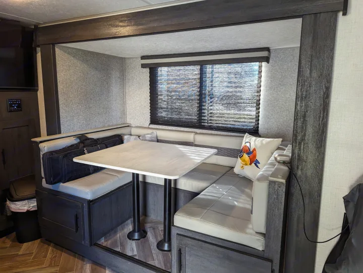 RV rental dinette area with U-shaped bench seating, table, and window. Perfect for meals or relaxing in your travel trailer.. Forest River 2700TH 2021