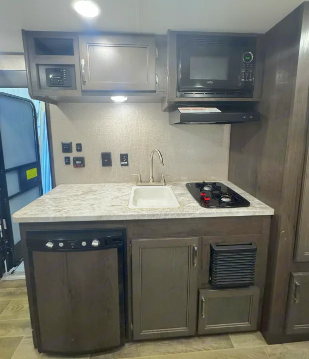 RV rental kitchen: compact design with sink, stove, microwave, fridge, and ample cabinets.. Jayco Jay Flight SLX7 184BS 2021
