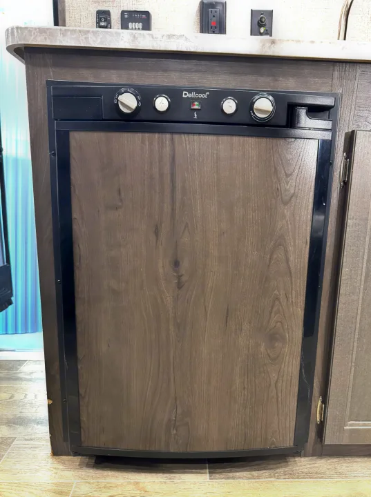 RV rental appliance: A modern Dellcool refrigerator with a wood-paneled door and top controls, integrated into an RV.. Jayco Jay Flight SLX7 184BS 2021