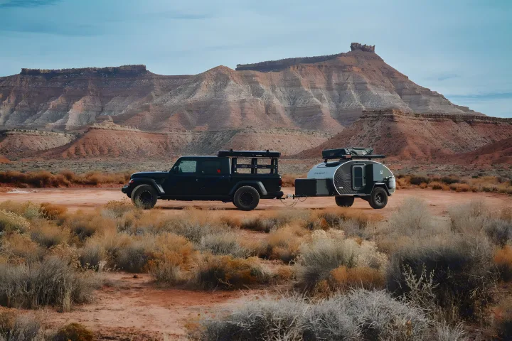Dark Jeep Gladiator towing a sleek teardrop RV rental. Perfect for desert adventures amidst red rock mountains.. Escapod Escapod Trailer 2022
