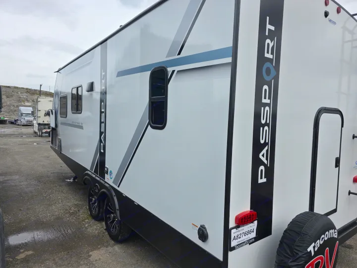 Modern white Keystone Passport travel trailer, ideal for an RV rental. Side and rear view with TacomaRV branding.. Keystone RV Passport SL Ultra Lite 2024