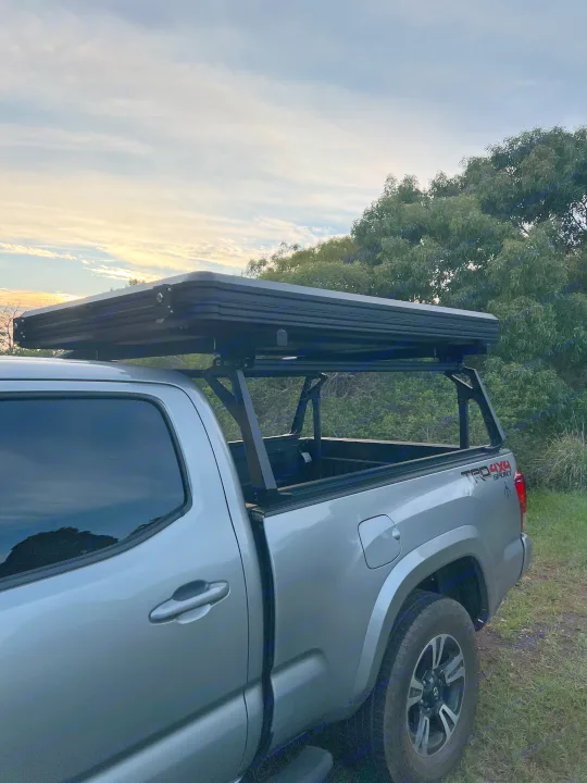 Silver pickup truck with rooftop tent for camping & adventure. Ideal as a versatile RV rental option.. Toyota Trailfinder 2016