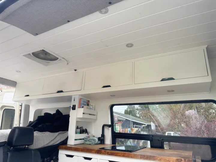 Spacious RV rental interior, showcasing a bright white ceiling, modern kitchen, cozy bed area, and overhead storage.. Mercedes-Benz Sprinter 2020