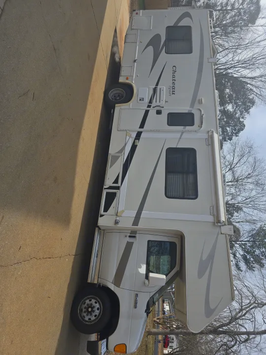 A white Chateau Sport RV, with black and grey graphics, parked on pavement. Generator exhaust visible; great for rv rental.. Four Winds Chateau Sport 2006