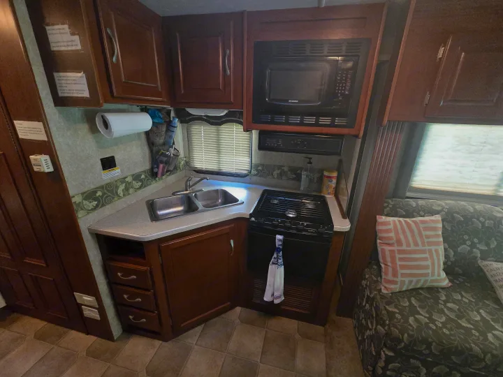 This RV rental features a compact kitchen area with a sink, stovetop, microwave, and cabinets, plus helpful usage instructions.. Four Winds Chateau Sport 2006