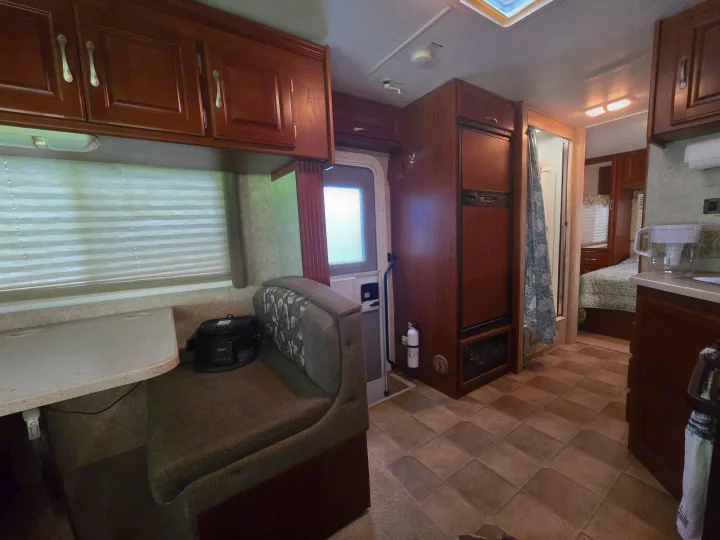Cozy rv rental interior featuring a dining booth, kitchen cabinets, refrigerator, and view into the bedroom and bathroom.. Four Winds Chateau Sport 2006