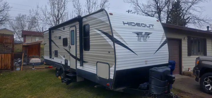 RV rental: A white and black Hideout travel trailer, parked on a grassy yard next to a residential house.. Keystone RV Hideout LHS 2018