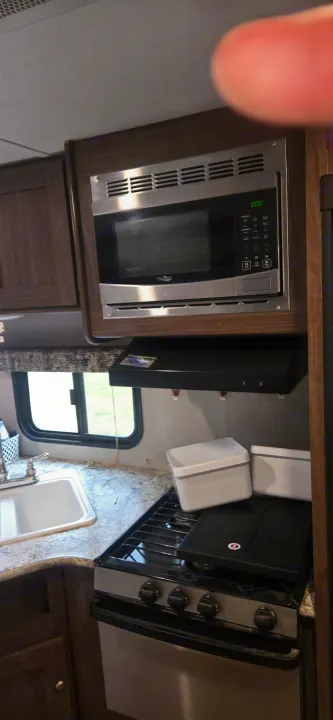 Inside an rv rental: A practical kitchen setup with a stainless steel microwave, gas stove, and sink.. Keystone RV Hideout LHS 2018