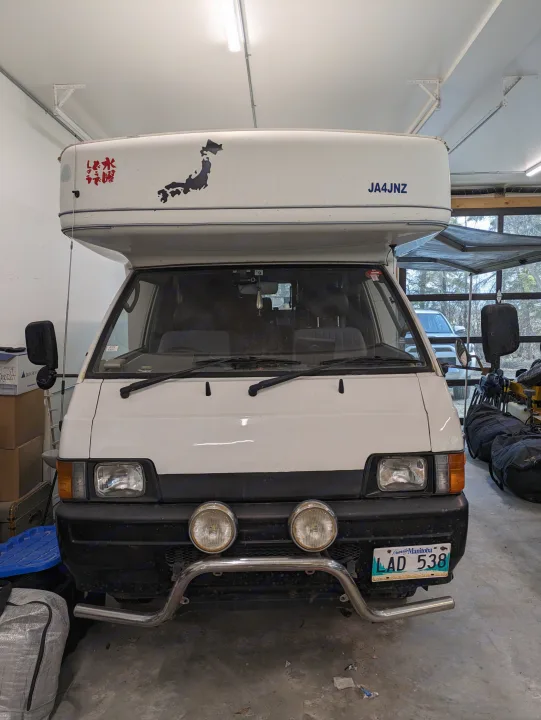 White Japanese import high-roof camper van for RV rental, with Japan map/text and Manitoba license plate.. Mitsubishi Delica JB470 1996
