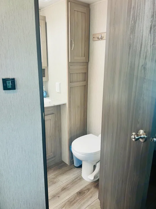 RV rental bathroom features a clean toilet, sink vanity, and ample cabinet storage, boasting modern light wood-look finishes.. Coachmen Freedom Express 2020