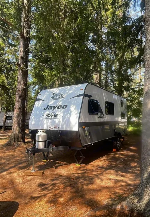 Jayco travel trailer RV rental parked at a peaceful wooded campsite. Ready for your next outdoor camping trip.. Jayco Jay Flight SLX STX Edition 2022