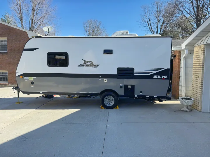 White and gray Jayco RV rental parked on a sunny concrete driveway.. Jayco Jay Flight SLX 2022