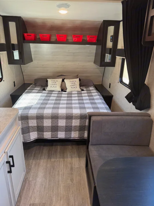 Inside an RV rental: a cozy bedroom with plaid bedding, overhead storage, and a dinette. Ready for comfortable adventures.. Jayco Jay Flight SLX 2022