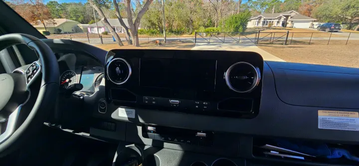 RV rental van interior: dashboard, steering wheel, and instruments (71°F, 10:45). Sunny view of a residential street, with safety warnings.. Mercedes Coleman 24CL 2024