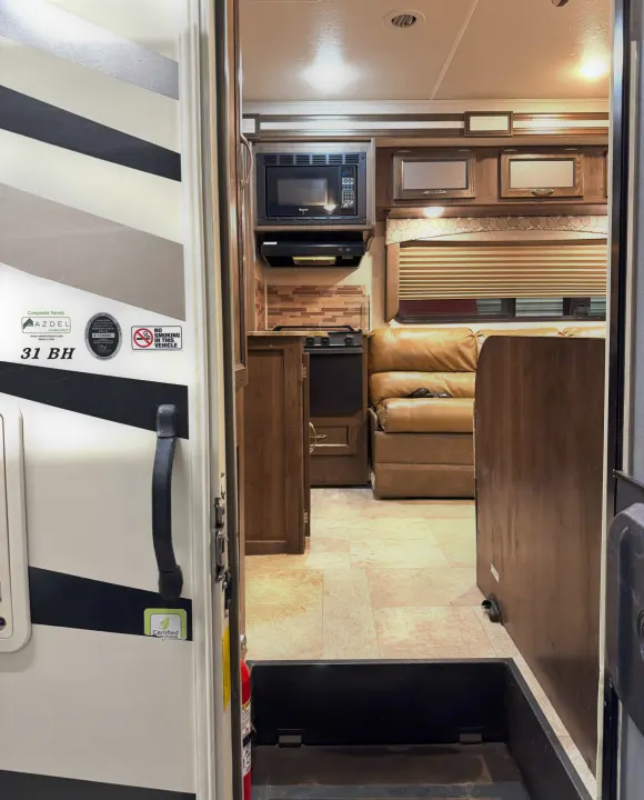 RV rental interior: kitchen with microwave, stove, and comfy leather sofa in the living area. A bright, clean motorhome space.. Coachmen Freelander 2020