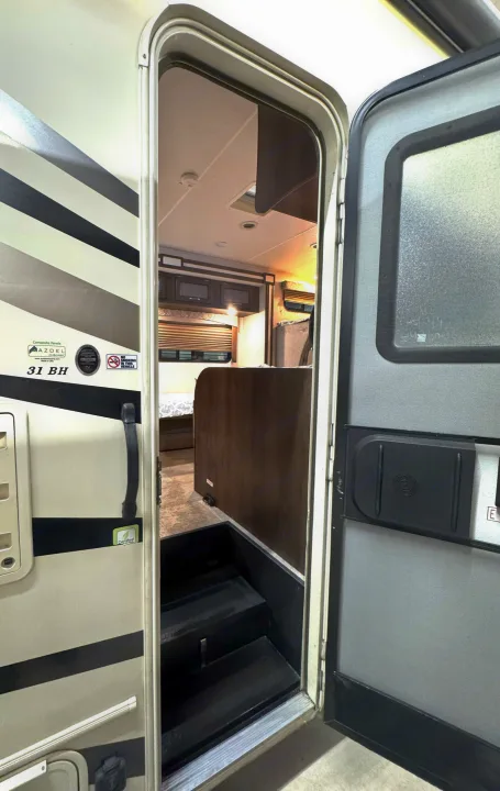 Exploring an RV rental: open door reveals interior with entry steps, bunkhouse, and living space of a 31 BH travel trailer.. Coachmen Freelander 2020