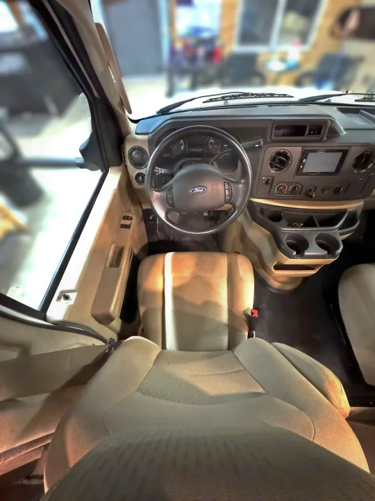Explore the spacious interior of this RV rental, featuring the driver's seat, Ford steering wheel, and dashboard from an elevated perspective.. Coachmen Freelander 2020