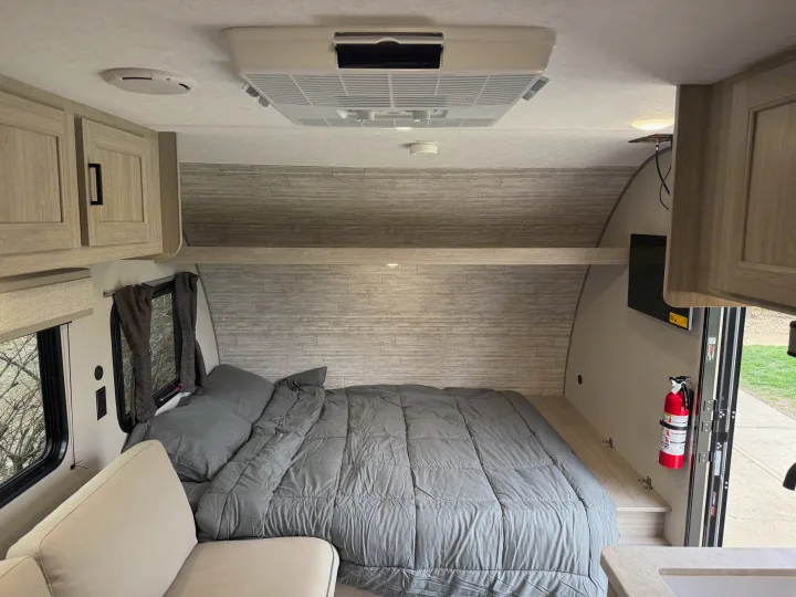 Clean RV rental interior: a comfortable bed, overhead AC, wall-mounted TV, and functional storage cabinets.. Forest River Coachmen Catalina Summit 2024