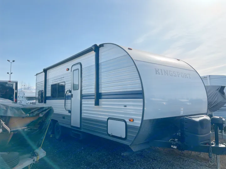 A silver Kingsport travel trailer, often seen as an RV rental, is parked outdoors under a clear sky with other vehicles.. Gulf Stream Kingsport 2021