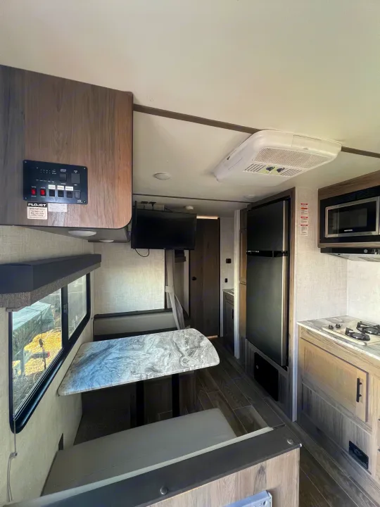 Spacious RV rental interior featuring a dinette, full kitchen (microwave, stove, fridge), and control panel. Ready for your trip!. Gulf Stream Kingsport 2021