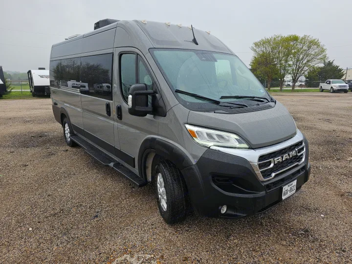This grey RAM ProMaster camper van for RV rental is parked on a wet gravel lot, ready for your next adventure.. Thor Motor Coach Twist 2026