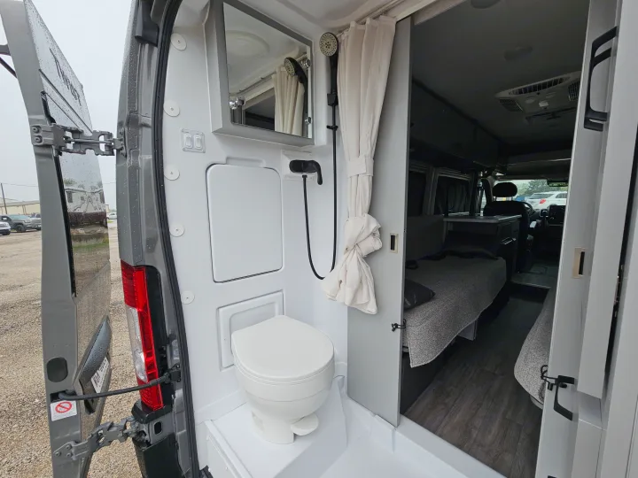 This RV rental's interior reveals a cleverly designed compact bathroom with toilet and shower, adjacent to a cozy sleeping area.. Thor Motor Coach Twist 2026