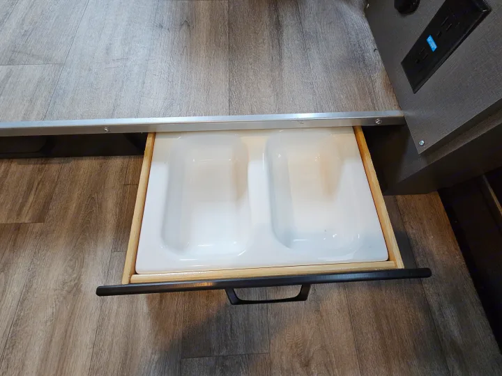 RV rental interior view: A pull-out drawer with two white utility basins. An electrical outlet is visible on the right.. Thor Motor Coach Twist 2026