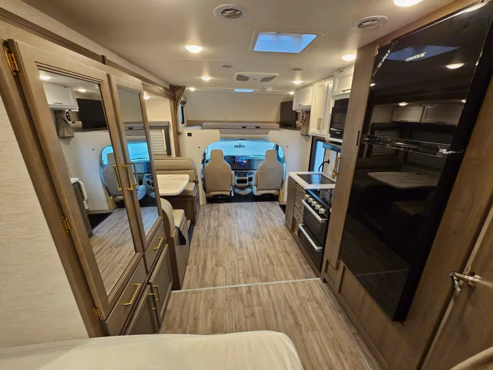 Spacious RV rental interior with modern kitchen, dinette, mirrored closets, and a cozy cab-over bunk.. Thor Motor Coach Four Winds 2026