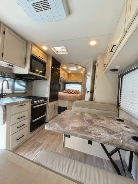 Spacious rv rental interior featuring a fully equipped kitchen, cozy dinette, and comfortable rear bedroom setup.. Thor Chateau 2023
