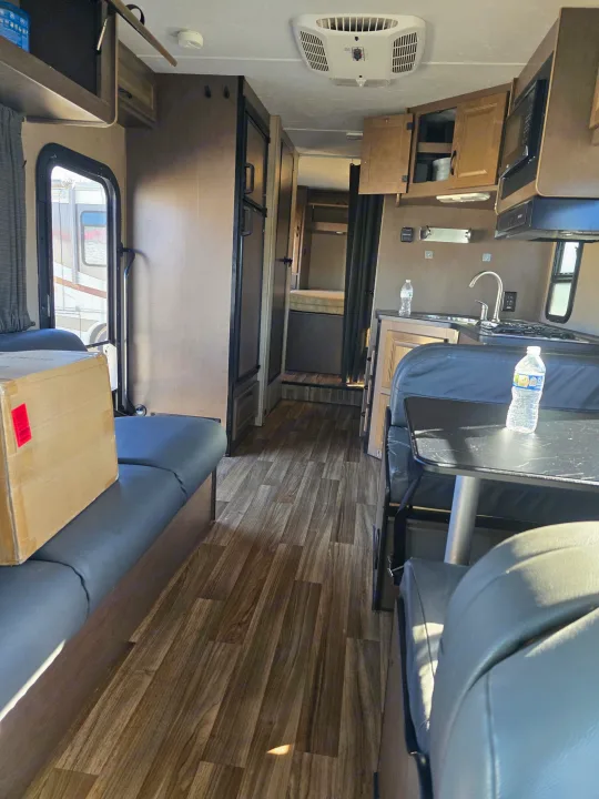 Interior view of an RV rental: kitchen, dining area, and hallway to the bedroom. Modern design for comfortable travel.. Thor Majestic 2019