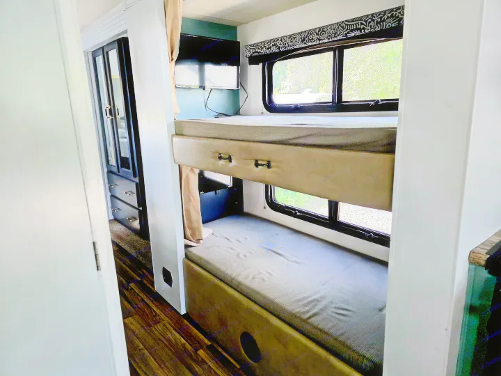 Experience comfort in this RV rental's bunk bed area with TV, storage, and a view of nature outside.. Thor Motor Coach A.C.E 2018