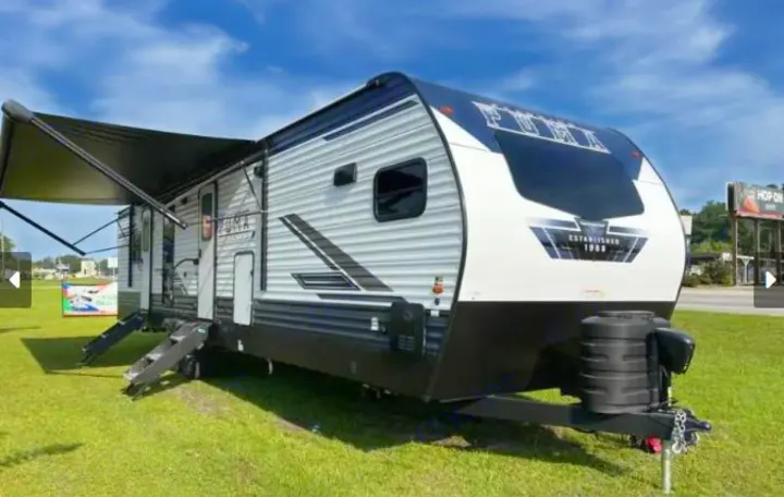White & black Puma travel trailer RV with awning extended, perfect for your next rv rental camping adventure.. Forest River Palomino Puma 2021
