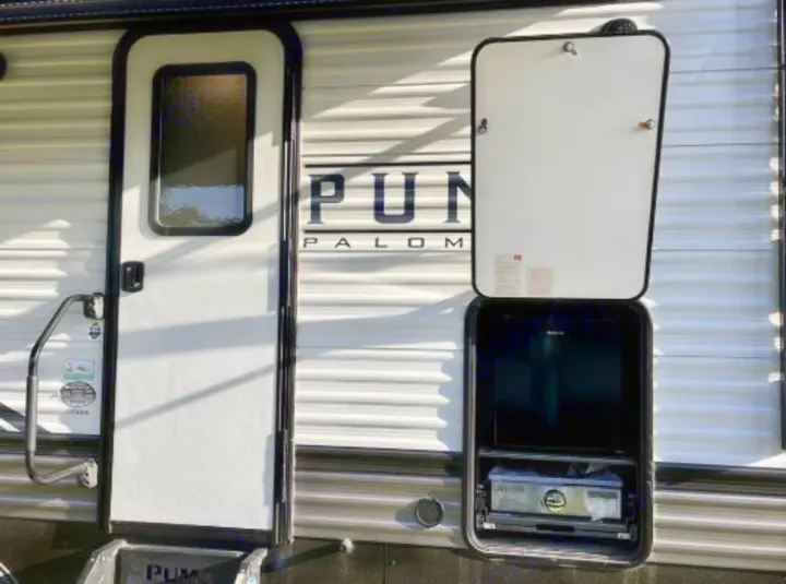 RV rental showing its entry door and an open outdoor kitchen with a pull-out grill. Perfect for camping adventures!. Forest River Palomino Puma 2021