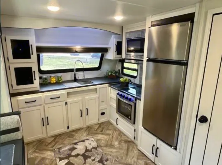 RV rental: Bright, modern kitchen interior with full-size fridge, microwave, stove, and white cabinets.. Forest River Palomino Puma 2021