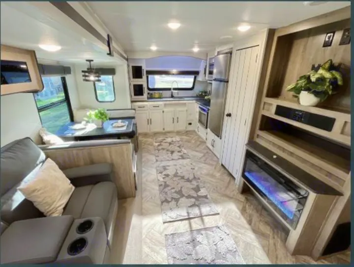 Spacious, modern RV rental interior with living, kitchen, dining areas & an electric fireplace.. Forest River Palomino Puma 2021