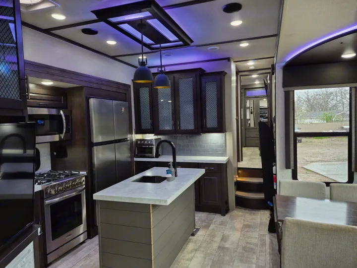 Modern RV rental interior: spacious kitchen with island, dining area, and stylish lighting.. Grand Design Momentum 2022