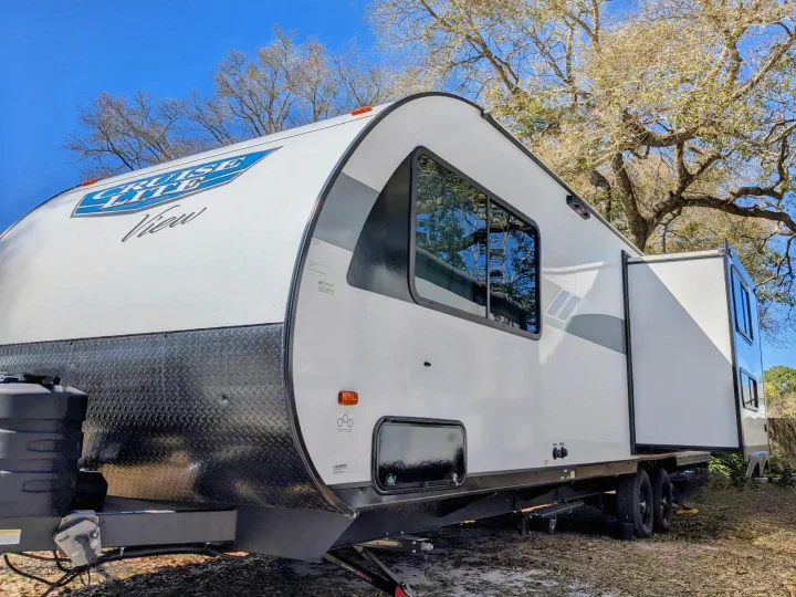 Bright white travel trailer RV rental, a Cruise Lite View model with slide-out, parked at an outdoor campsite.. Forest River Salem Cruise Lite 2024